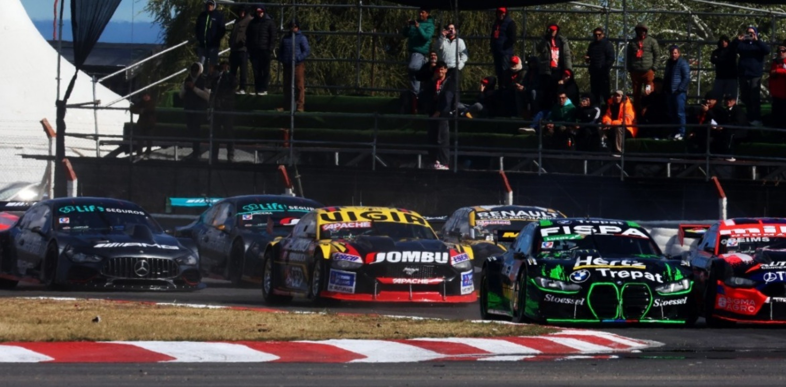 Competencia de Turismo Carretera en pista con varios vehículos disputando posiciones.