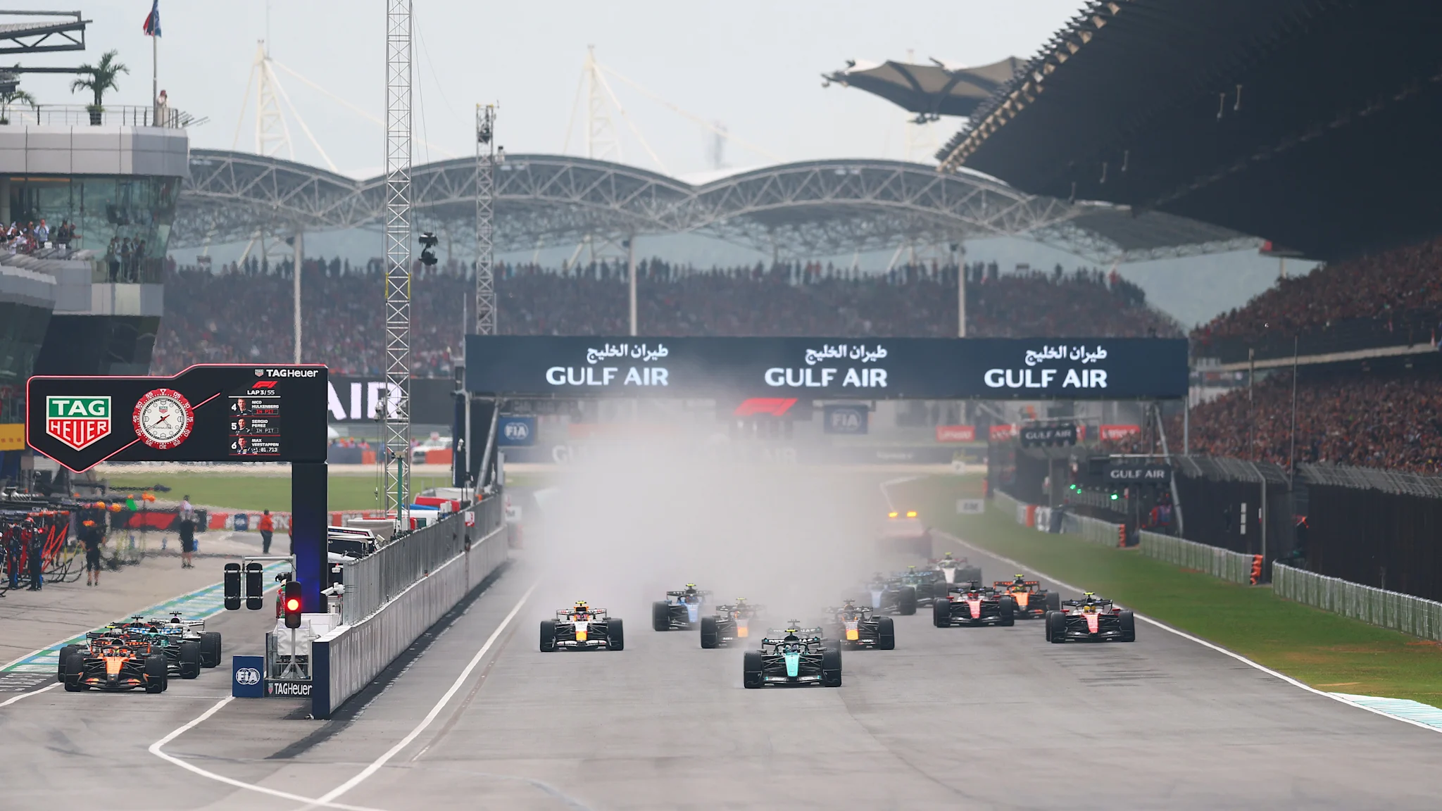 Monoplazas de Fórmula 1 en la largada bajo condiciones mixtas en el circuito de Sepang