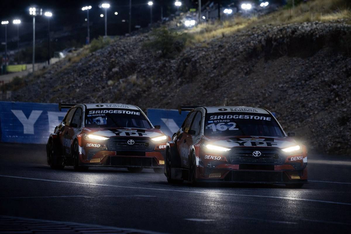 Dos autos del TC2000 girando de noche en una pista iluminada