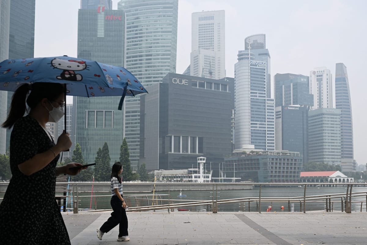 Una persona camina con paraguas bajo el aire contaminado en la zona urbana de Singapur previa al Gran Premio de Fórmula 1.