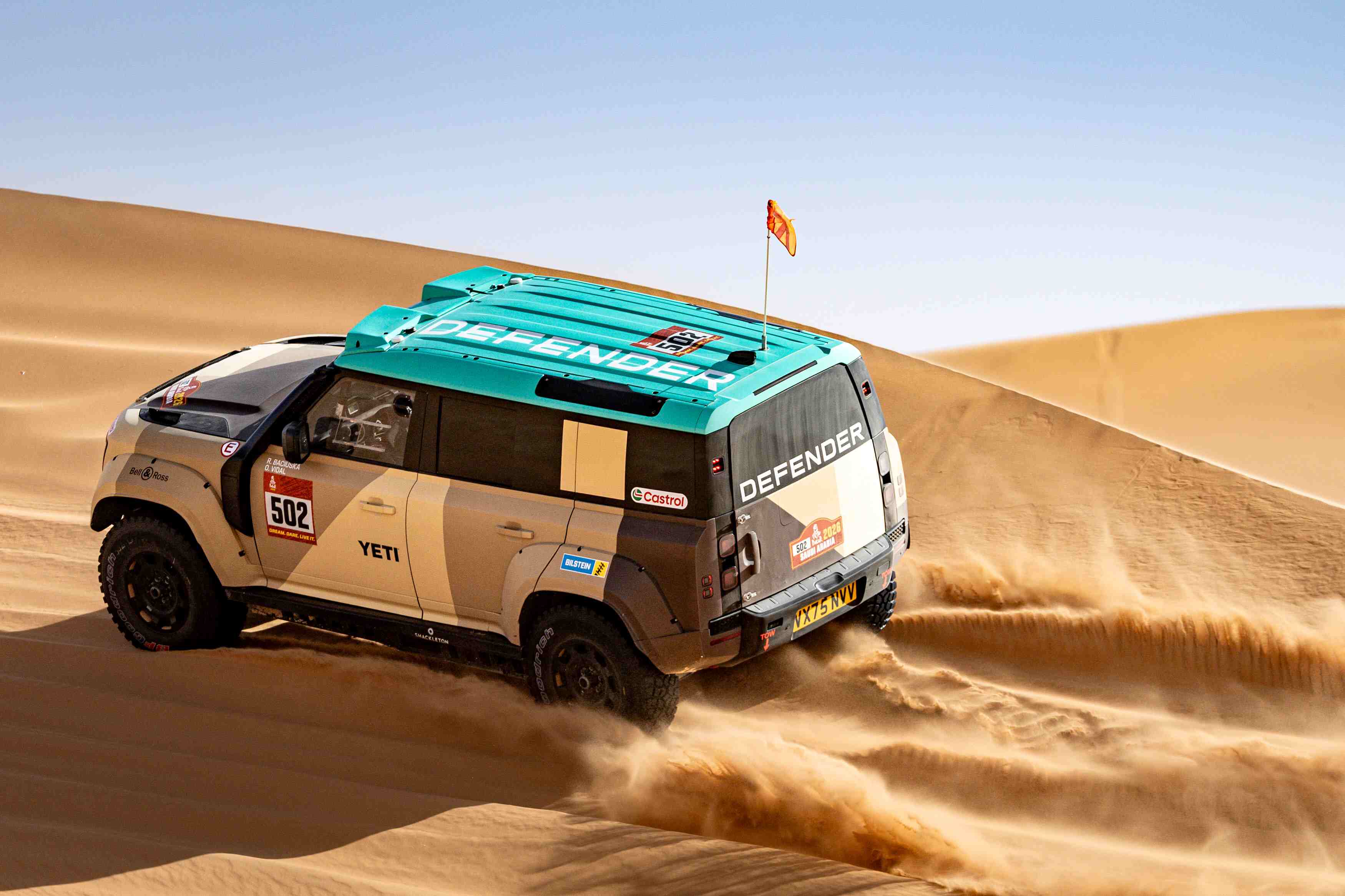 Vehículo todoterreno en plena aceleración sobre las dunas de arena durante una competencia de rally raid.