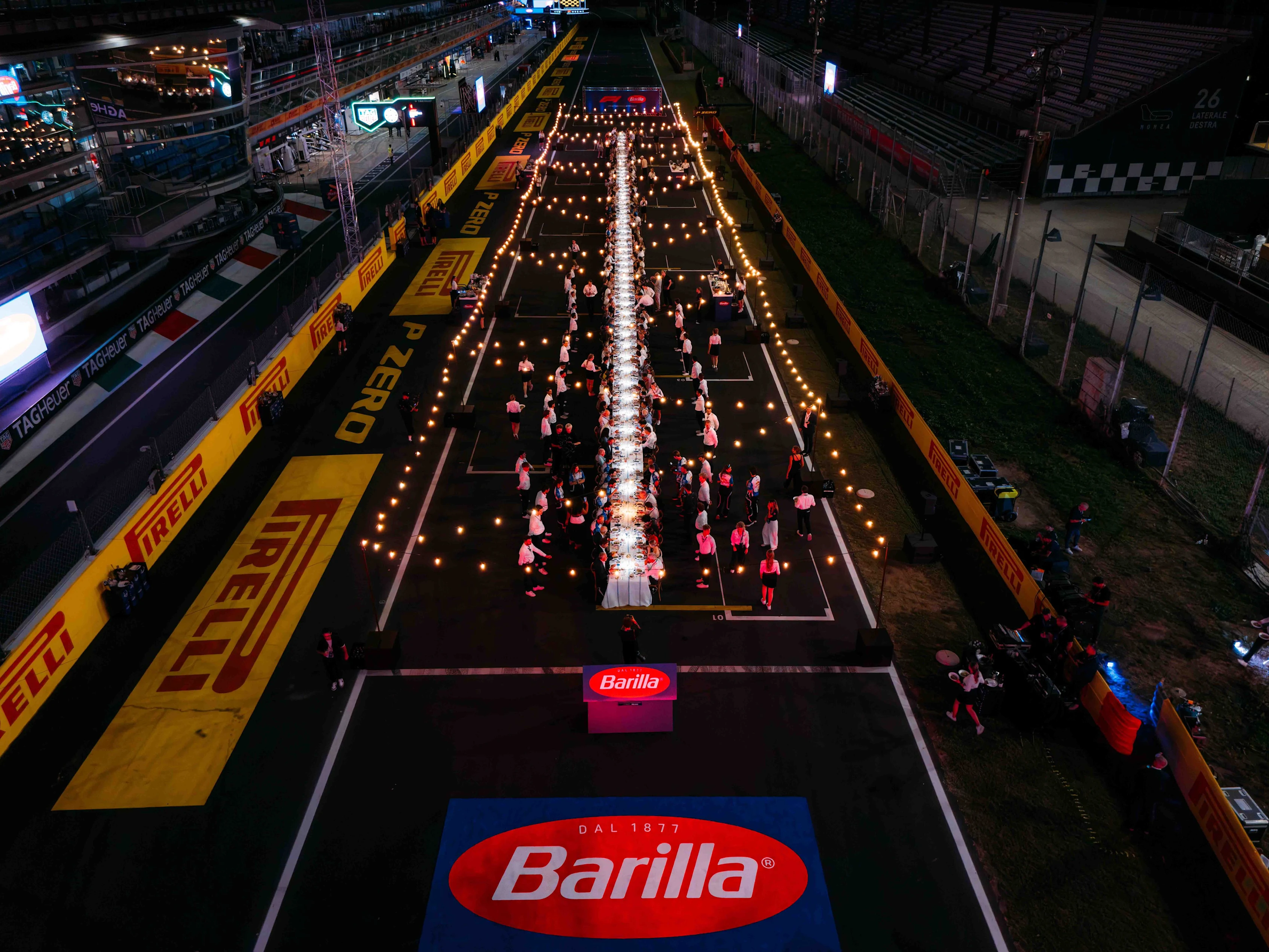 Vista aérea de la larga mesa dispuesta sobre la grilla de salida del circuito de Monza durante el evento.
