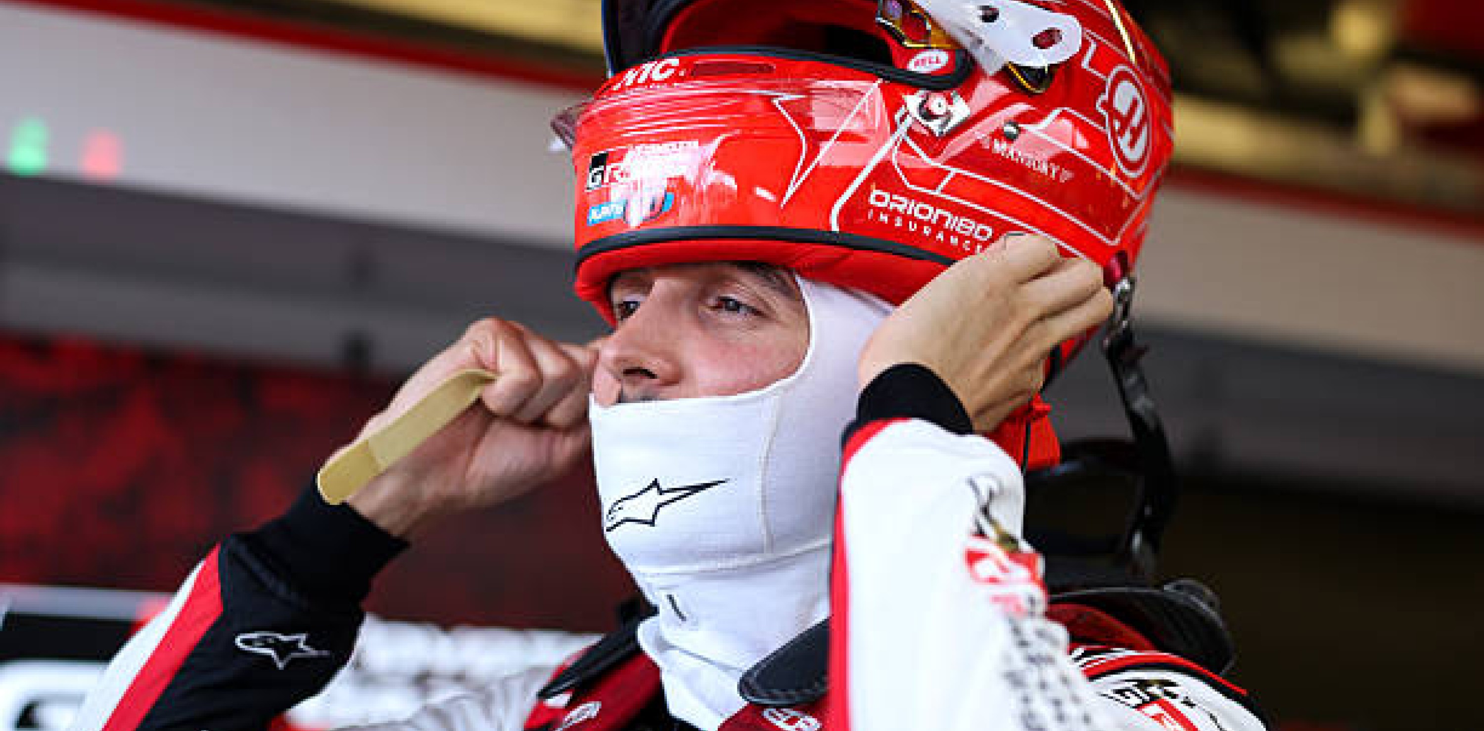 Esteban Ocon ajustándose el casco en el box de Haas durante una jornada de Fórmula 1.