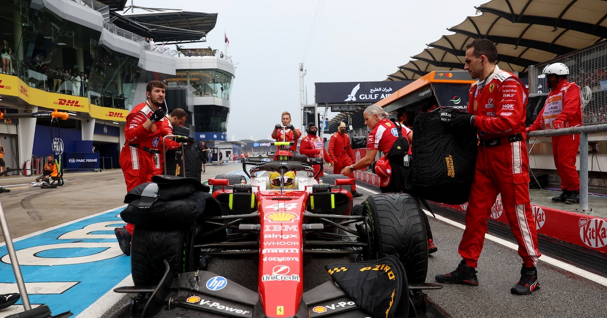 Personal de la escudería Ferrari trabajando en los monoplazas bajo la lluvia en el circuito.